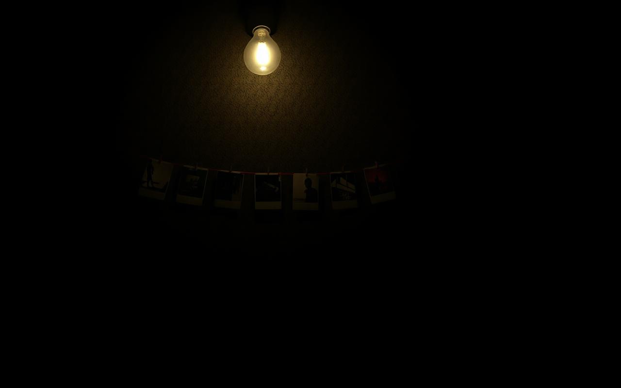 Photographs pinned across a wall under a single bulb